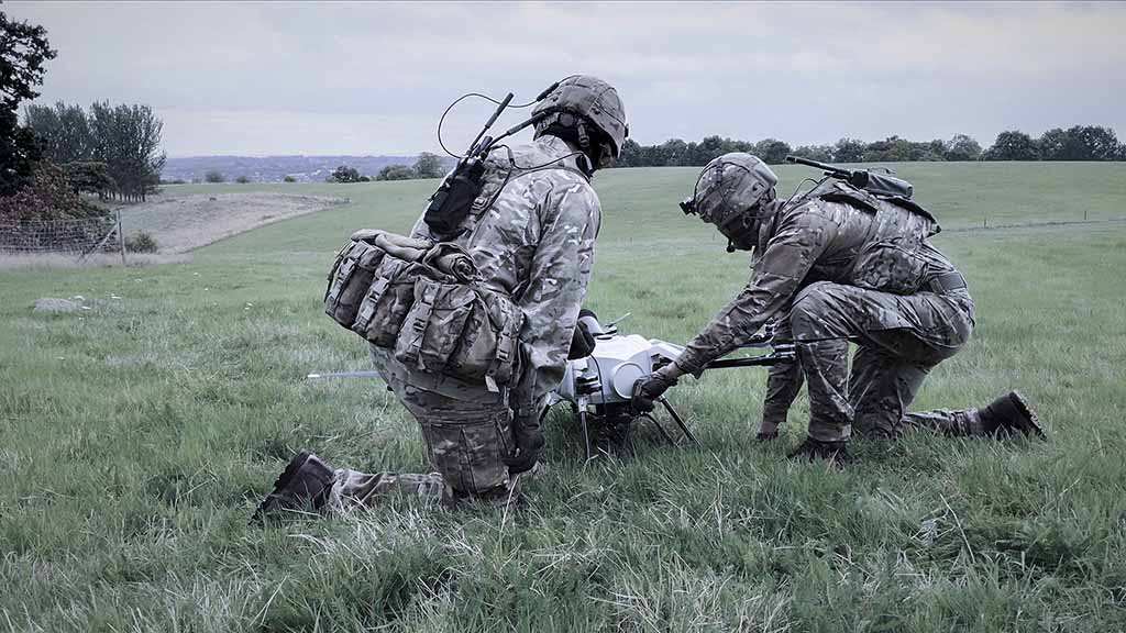 2 UK Soldiers equipped with communication radios are setting up Elistair Orion military drone