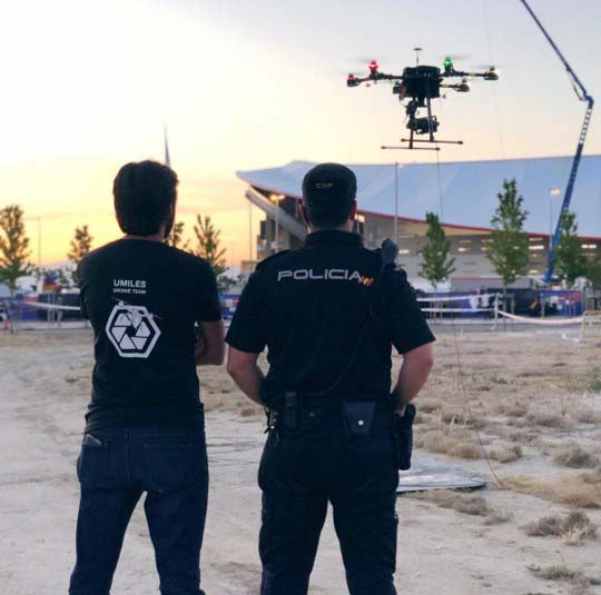Two police officers posing confidently in front of a drone.<br />
