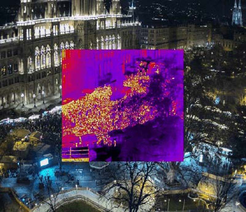 Aerial view of a large crowd at night with an overlay of thermal imaging to monitor the event