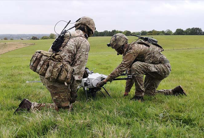 Soldiers assembling a tethered drone in a rural area.