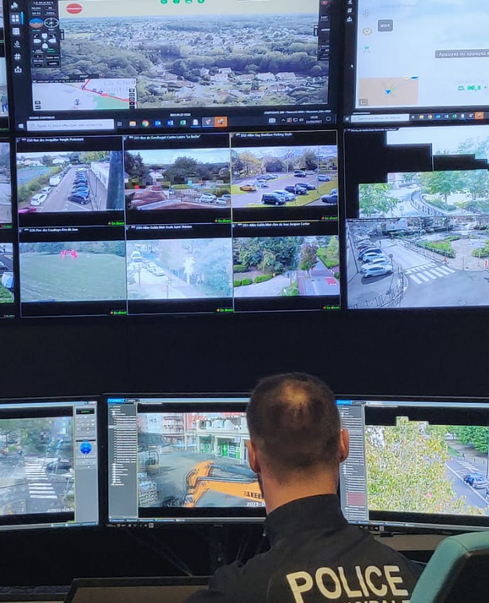 Police officer monitoring multiple surveillance camera feeds in a control room
