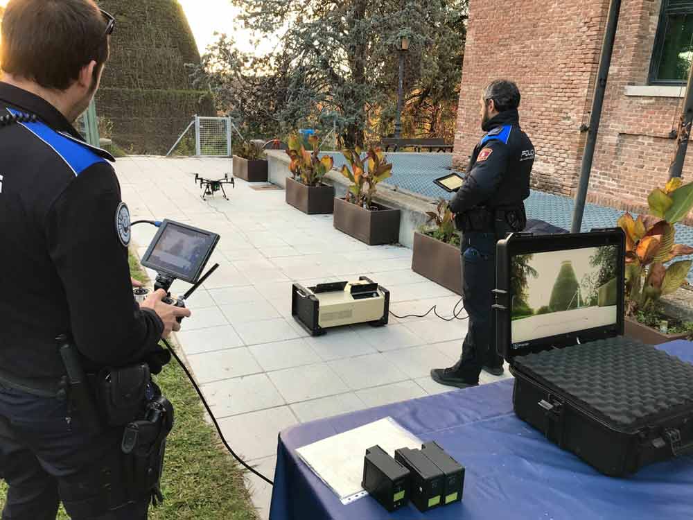 Police officers operating a drone with control tablets during an outdoor surveillance operation