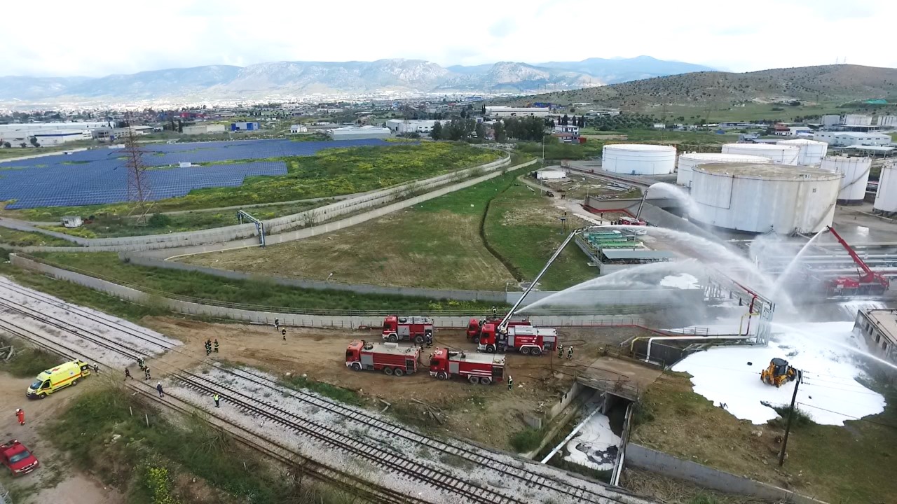 Fire trucks and firefighters responding to an industrial fire with drones