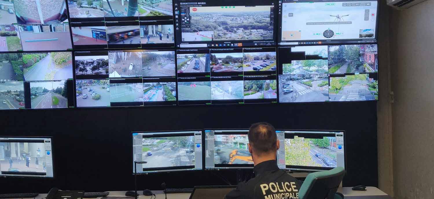 Police officer monitoring multiple surveillance camera feeds in a control room